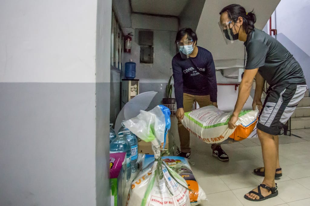 Two men carry a large bag of relief supplies.